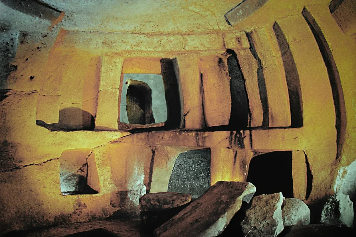 Entrance to the Ħal Saflieni Hypogeum, showing a modern walkway leading into a dimly lit ancient rock-cut structure.