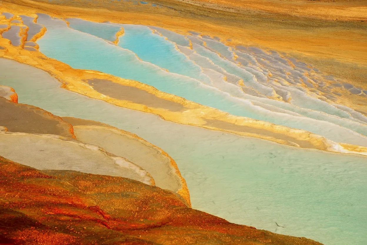 Panoramic view of Badab-e Surt's golden and orange travertine terraces in Iran