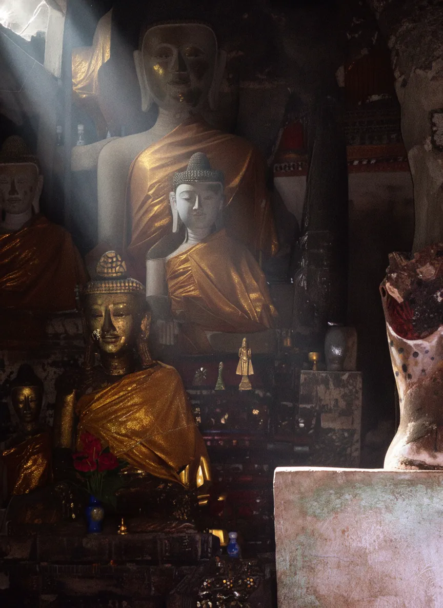 A closer view of a traditional shrine built into a natural cave opening in Ban Tham, adorned with offerings and flowers, showcasing the spiritual integration with the limestone karsts.