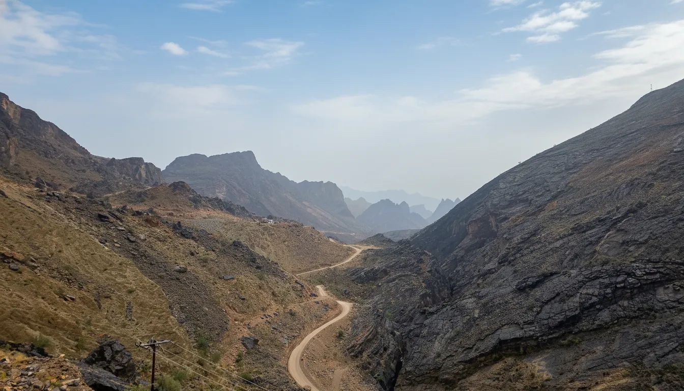 Panoramic view of Bilad Sayt village clinging to a steep mountainside in Oman, with terraced fields and traditional mud-brick homes.