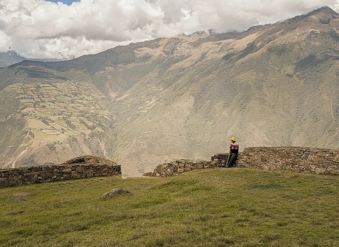 Panoramic view of Choquequirao's extensive terraces carved into a steep mountainside, with cloud forest and mountains in the background.