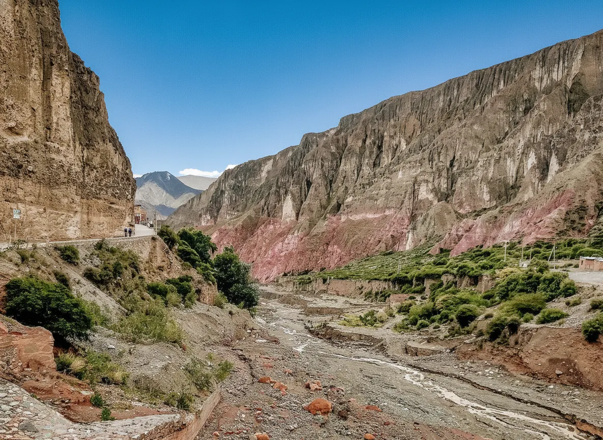 A narrow, winding dirt road carved into the side of a dramatic, multi-colored mountain, leading to Iruya.