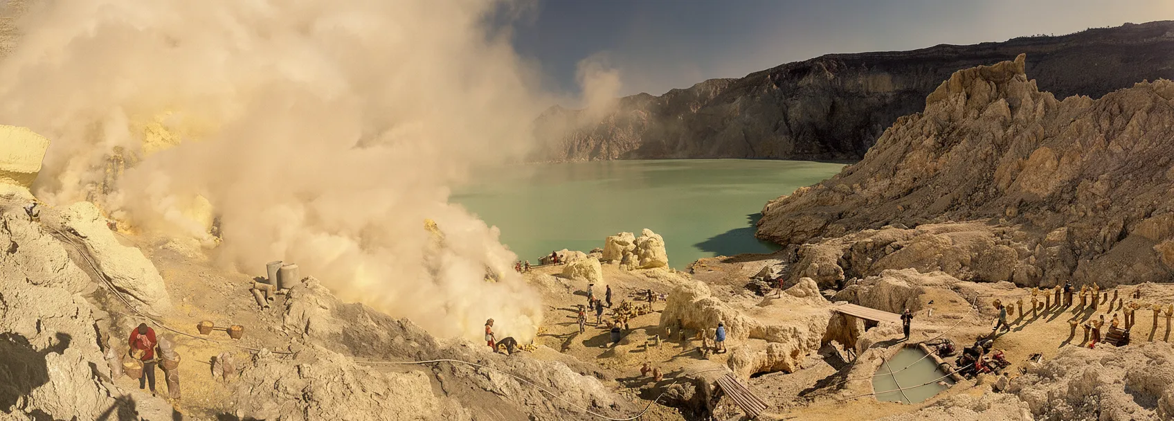 A sulfur miner carrying heavy baskets of yellow sulfur up the steep path of Kawah Ijen.