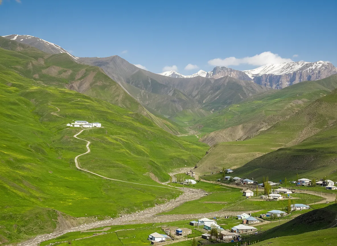 Panoramic view of Khinalug village, Azerbaijan, clinging to a steep mountain slope with stacked stone houses and surrounding green valleys.