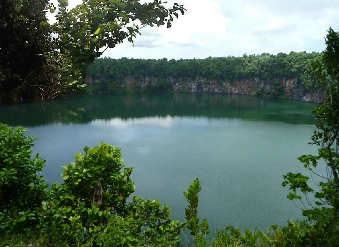 Aerial view of Lake Lalolalo, a perfectly circular volcanic lake surrounded by dense tropical rainforest on Futuna Island.
