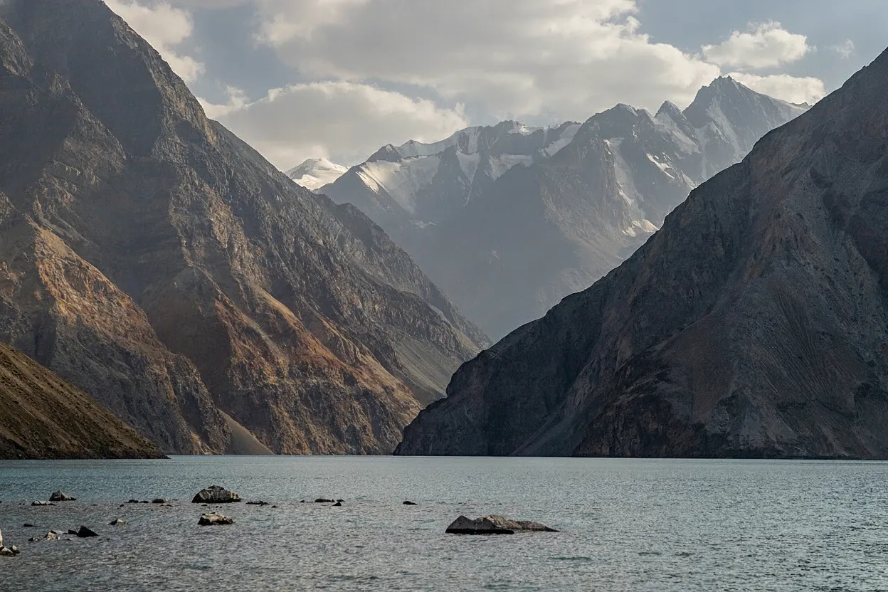 Close-up view of the clear, vibrant turquoise water of Lake Sarez, reflecting the sky and surrounding cliffs