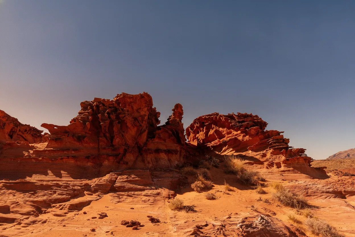 A hiker admiring the intricate red rock formations of Little Finland under a clear blue sky.