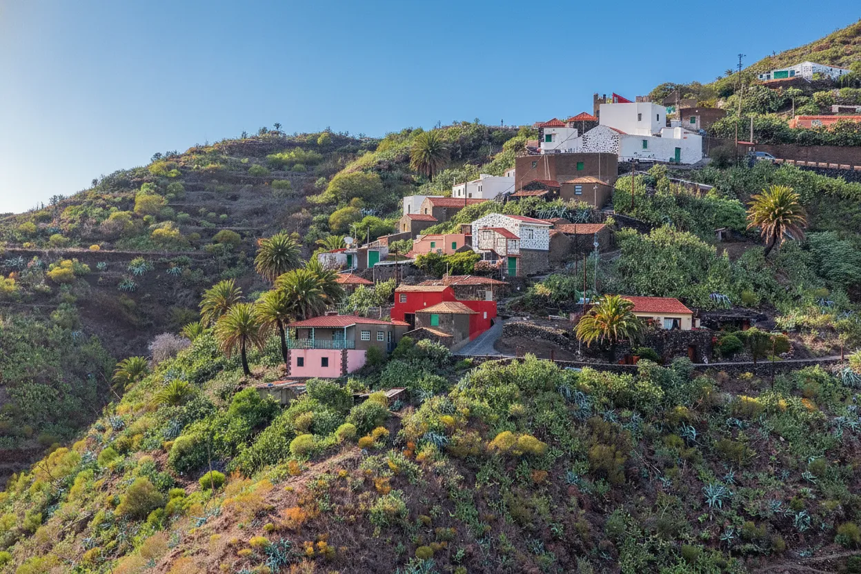 Panoramic view of Masca village clinging to a steep volcanic cliff face with dramatic ravines