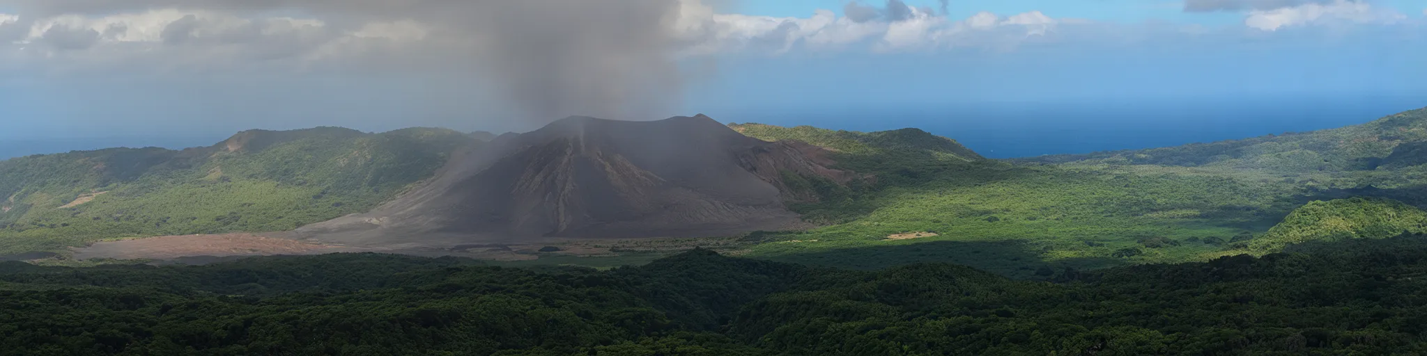 A group of tourists wearing protective gear, observing Mount Yasur at night