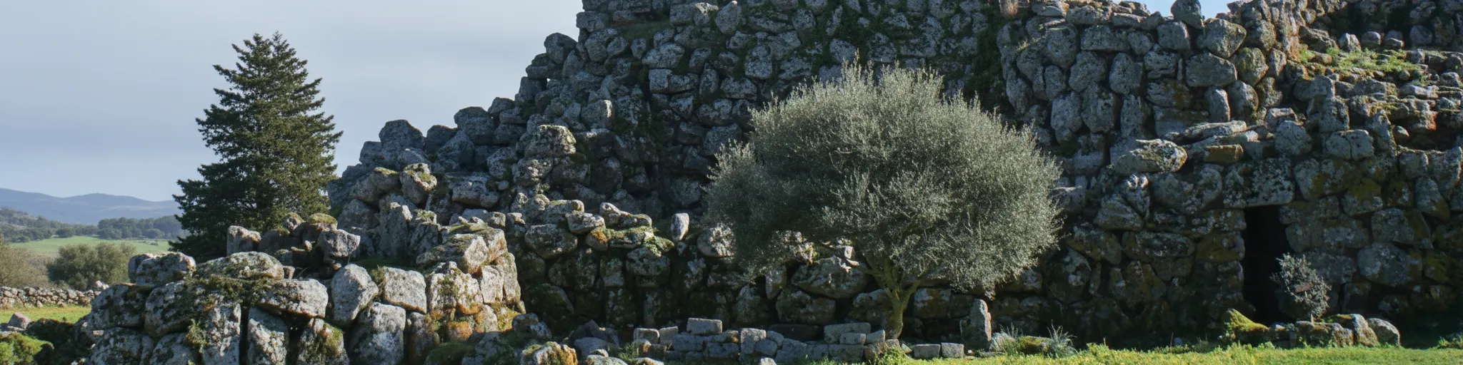 A visitor standing at the base of Nuraghe Arrubiu's central tower, looking up in awe at its massive stone construction.