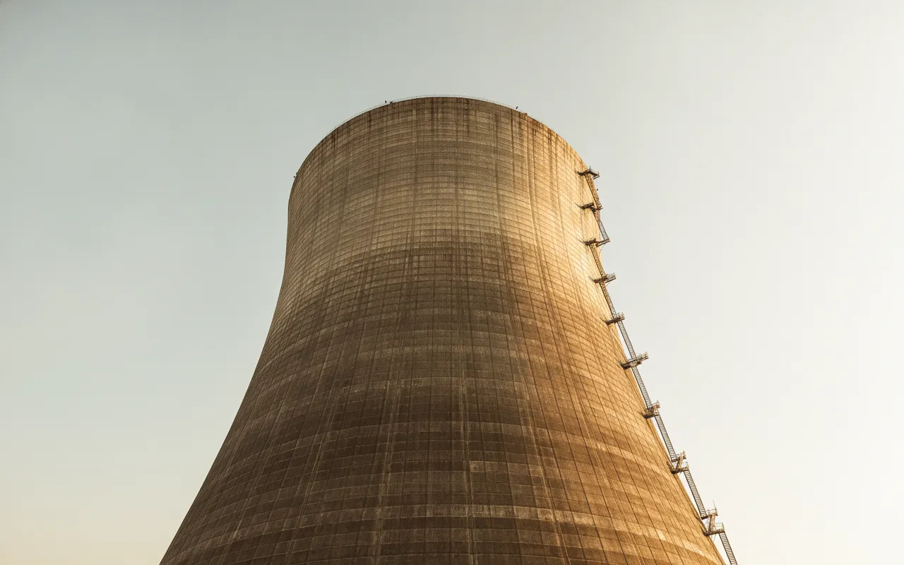 A wide-angle shot showing the two massive concrete cooling towers of the Satsop Nuclear Power Project reaching into the sky, with smaller industrial buildings in the foreground.