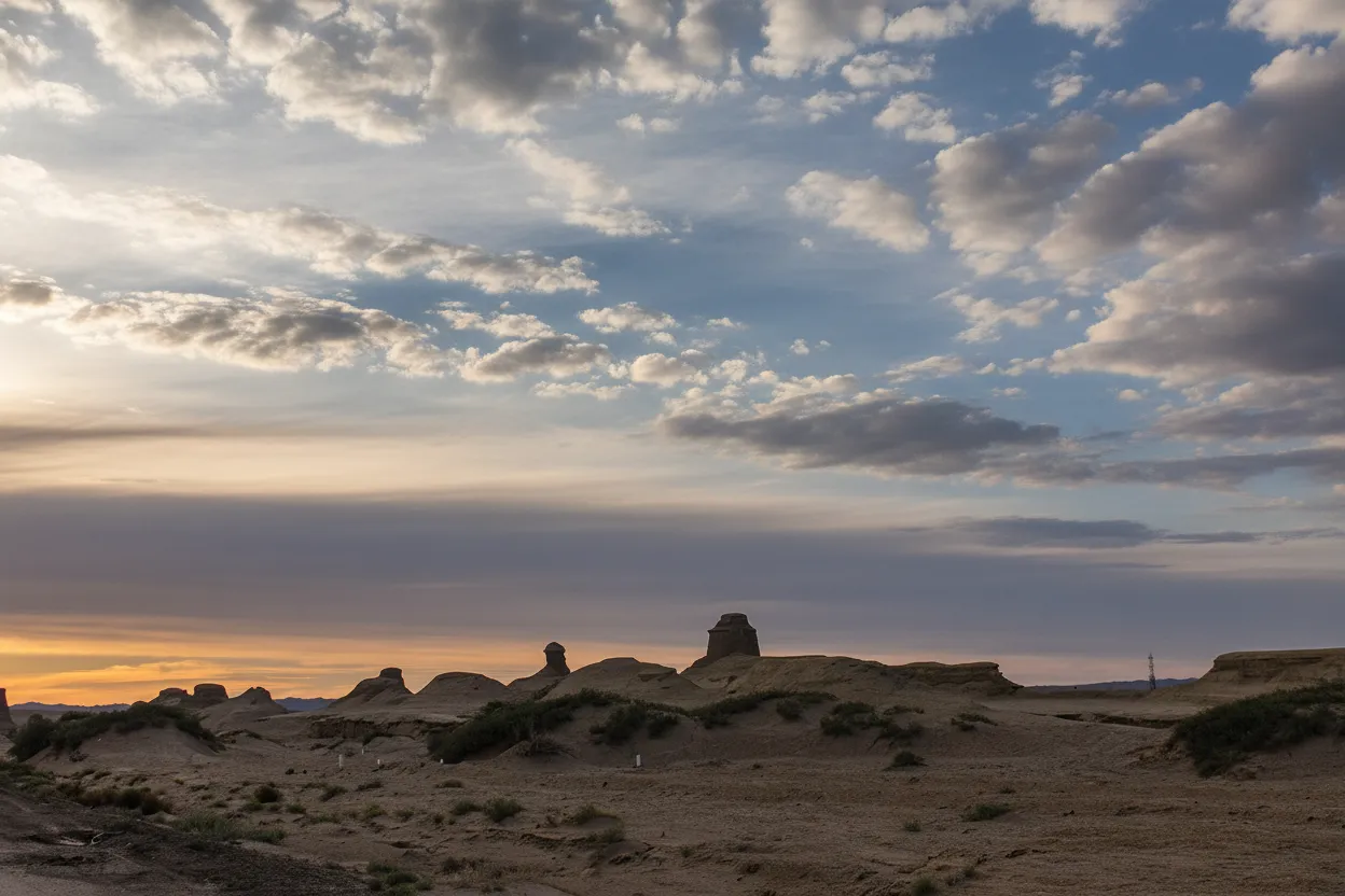 Vast panoramic view of Urho Devil City with numerous wind-sculpted Yardangs under a dramatic sky, showcasing their unique shapes and shadows.