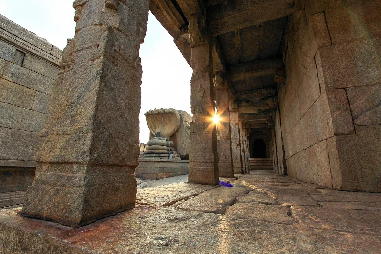 Close-up of the hanging pillar at Veerabhadra Temple, Lepakshi, with a cloth being passed underneath it, highlighting the gap.