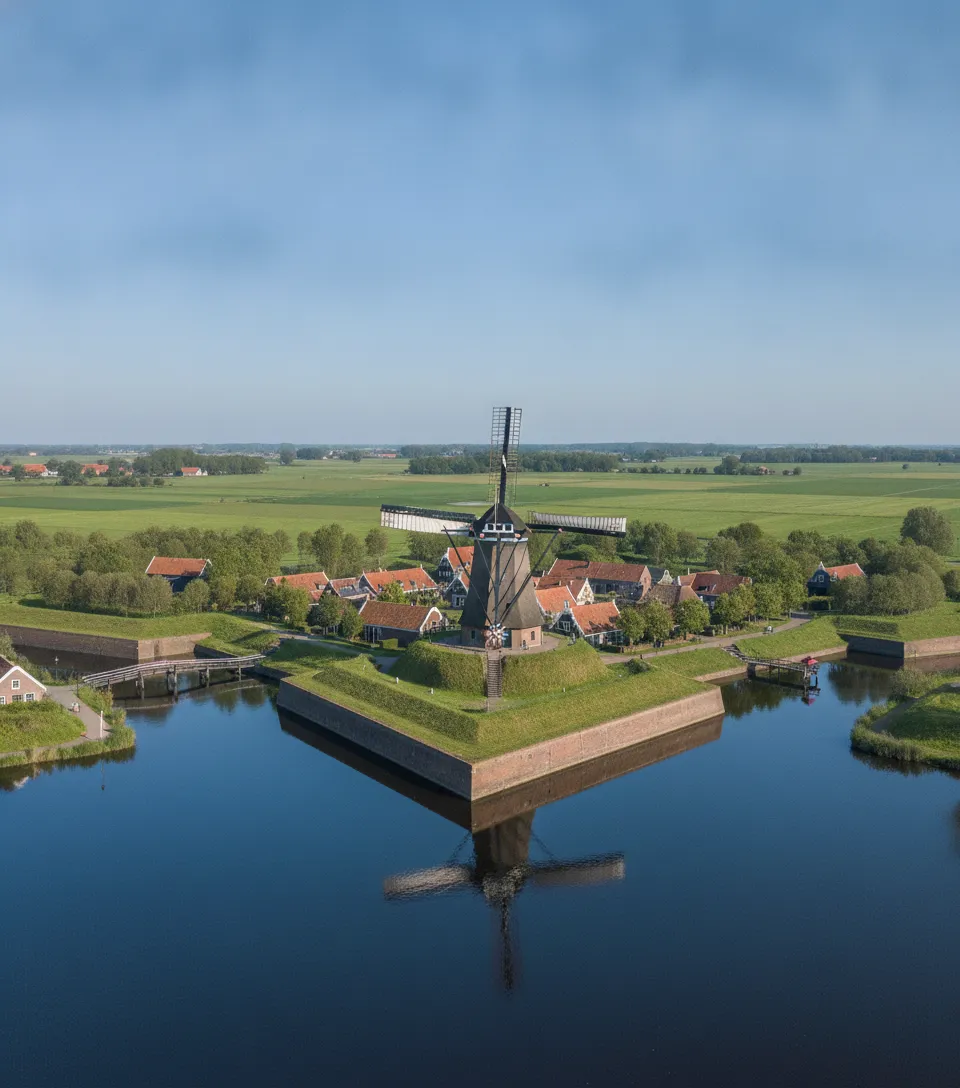 Historic cannon on the ramparts of Vesting Bourtange overlooking the moats and village buildings.