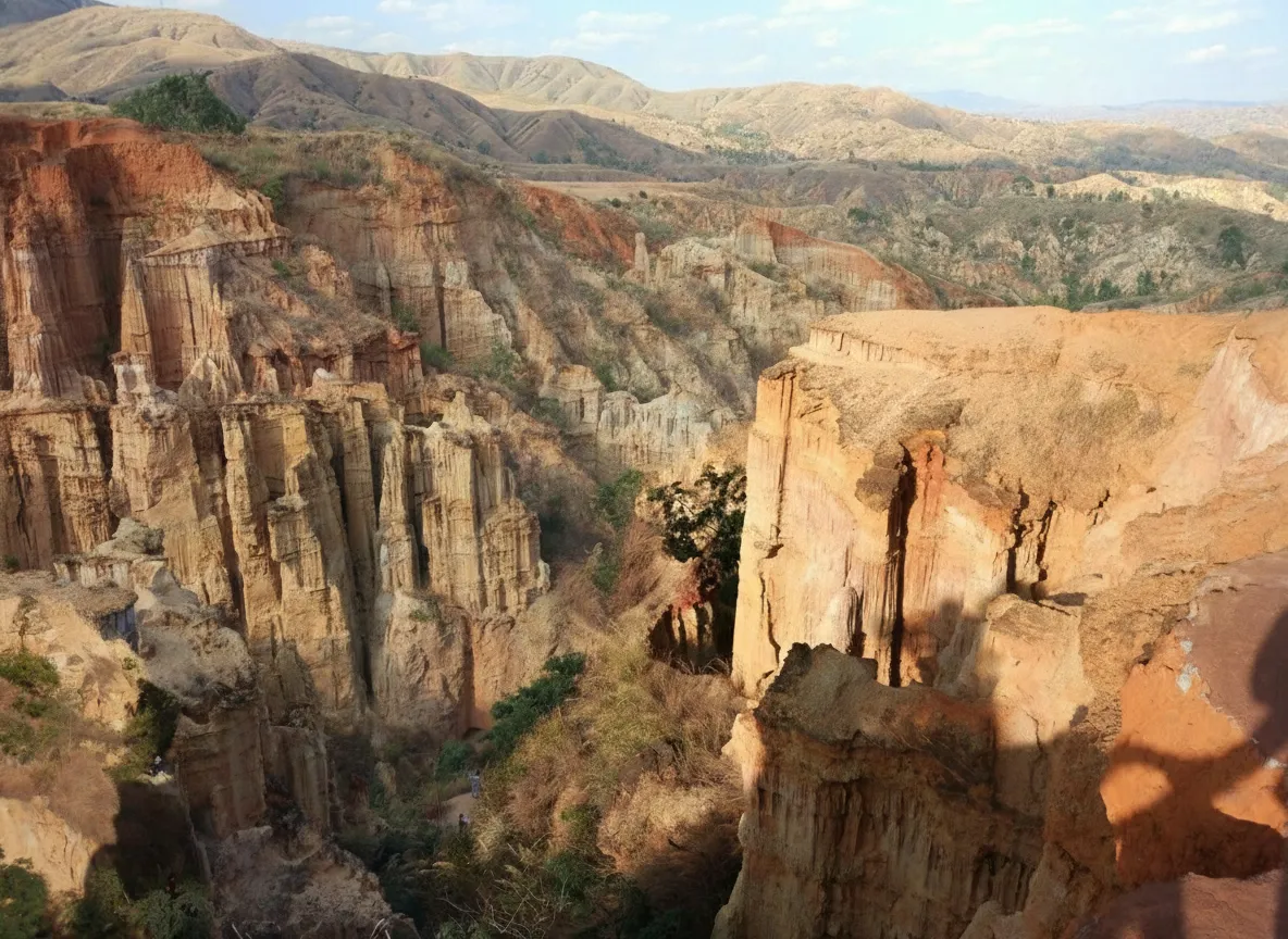 A person walking along a winding path through the Yuanmou Earth Forest, dwarfed by the towering earthen formations.